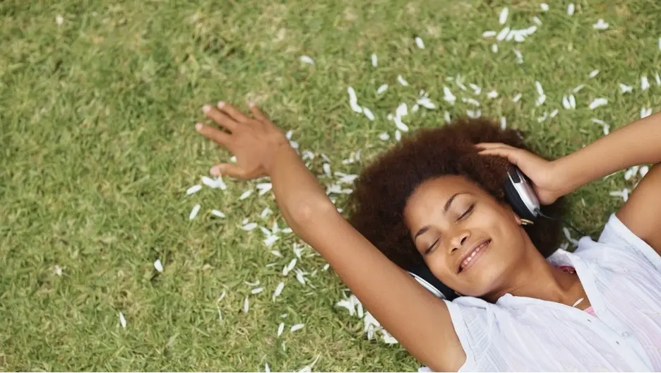 A person lying on the grass listening to music