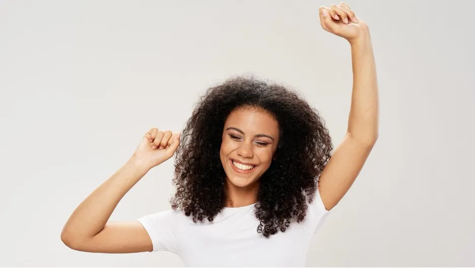 A person with curly hair raising her hands up