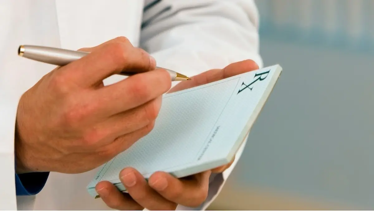 A medical professional writing on a pad of paper