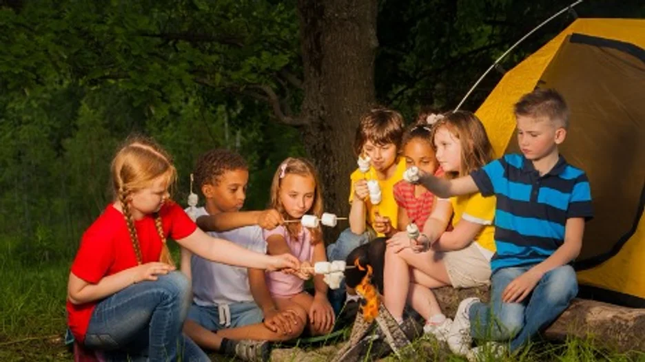 A group of kids roasting marshmallows on a campfire