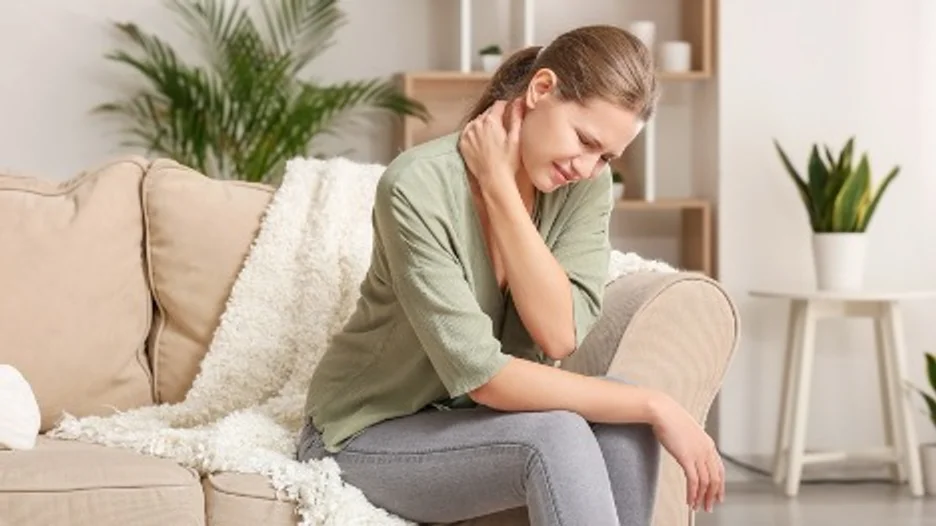 A person sitting on a couch with discomfort showing on their face