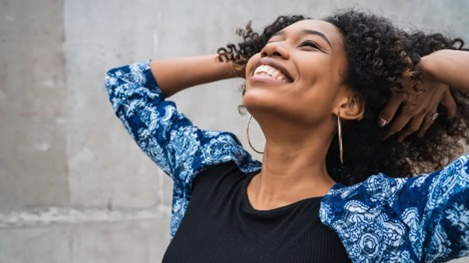 A person smiling with her hand behind her head