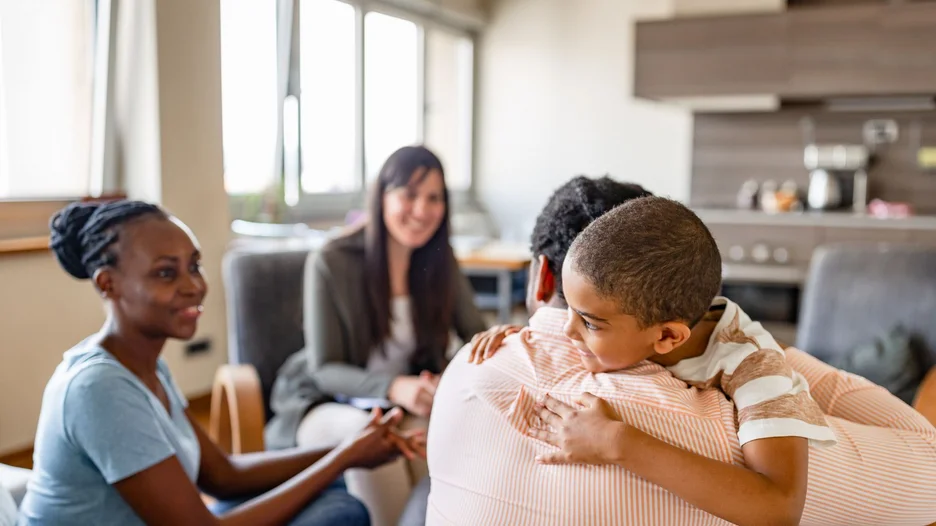 Three people talking to each other while a child is on the shoulder of one of them