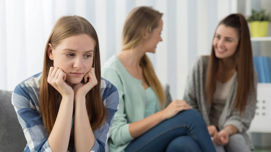 Two happy people talking together while one anxious person is alone